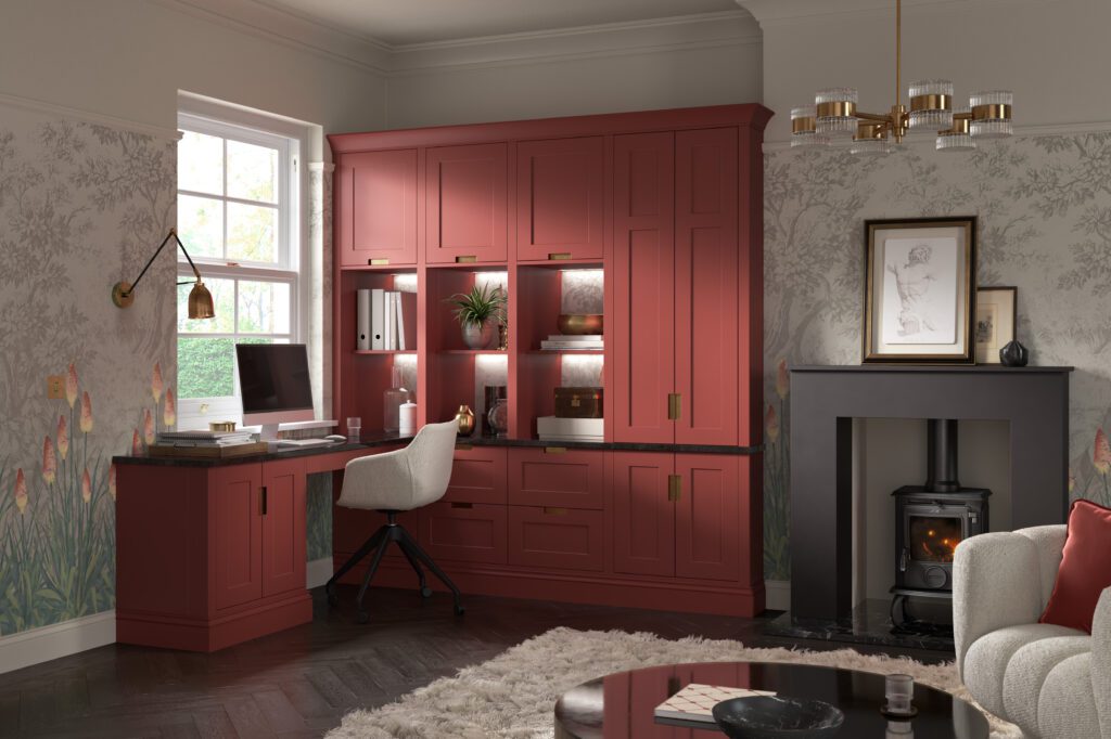 Bespoke red home office with fitted shaker-style cabinetry, integrated desk, illuminated display shelving, brass hardware and custom storage surrounding a dedicated workspace.