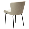 The back angle of the glam swivel chair in simply beige boucle with black metal legs.