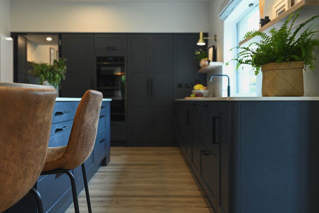 A navy kitchen with closed pantry doors, concealing a hidden pink interior, blending classic elegance with a modern design twist.