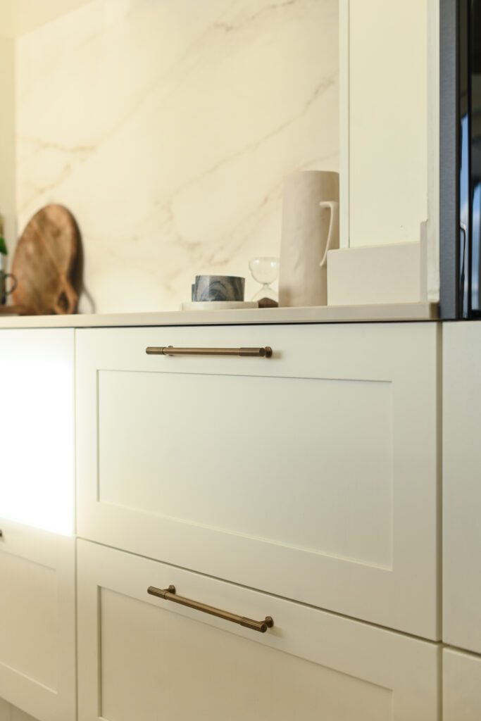 Shaker kitchen cabinetry in windborne white with built-in oven and brass handles in Tipperary home