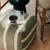 green striped pouf used as footstool beside armchair in modern living room
