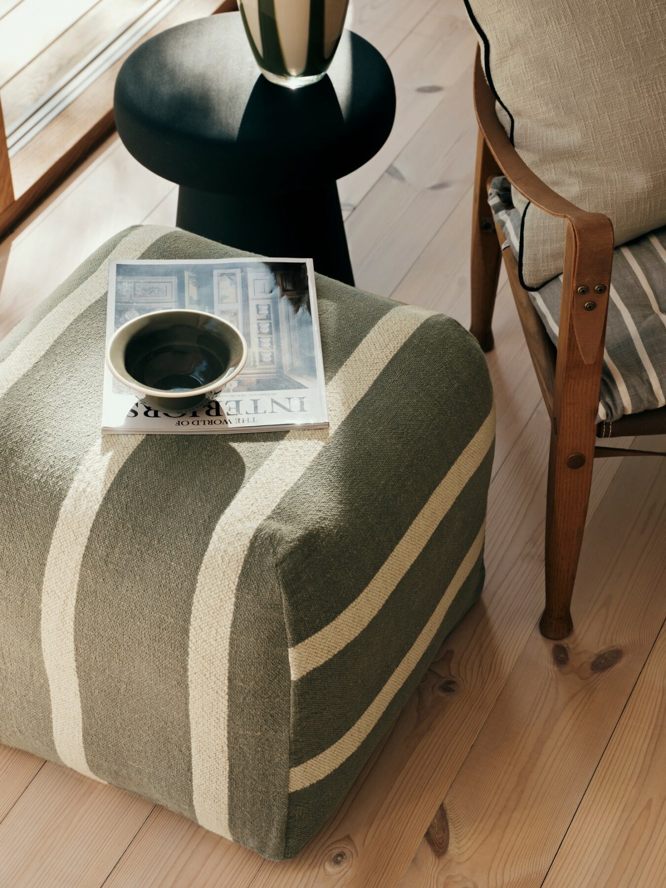 green striped pouf used as footstool beside armchair in modern living room
