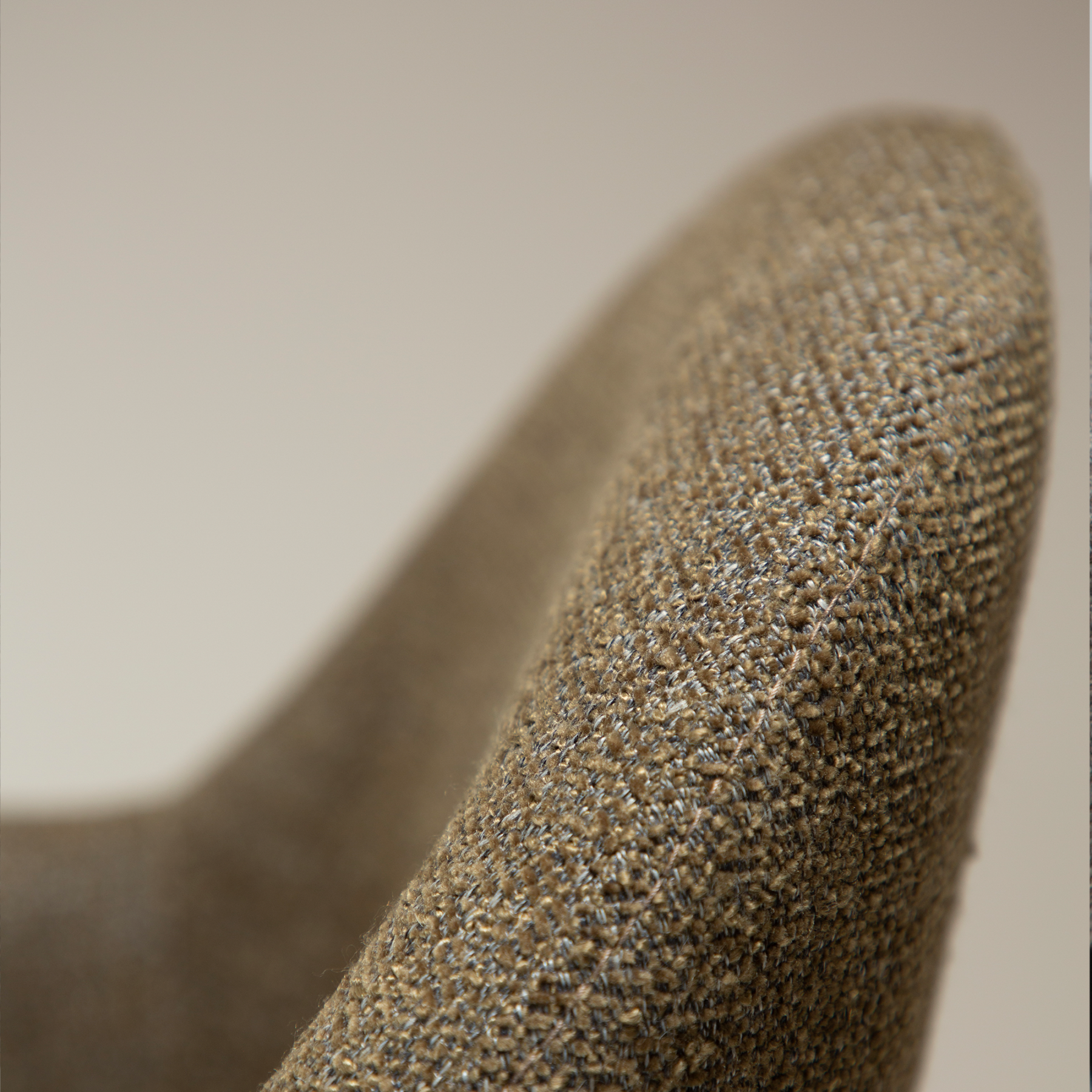 Close up of the dark olive boucle fabric on the BAE Armchair with antiquepewter swivel legs