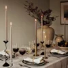 Large beige florentina vase with flowers on a table set for dinner with candles lighting