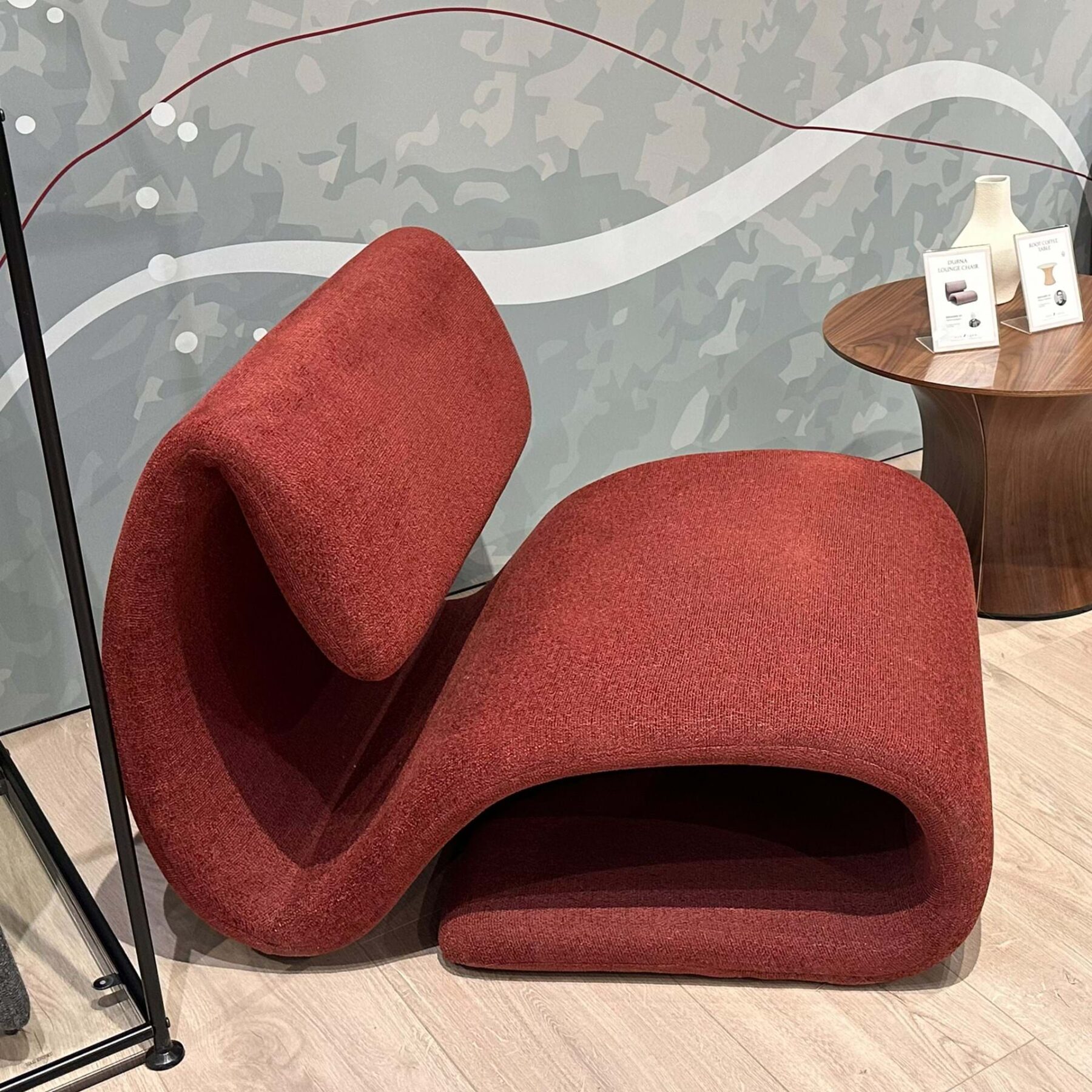 DUBNA lounge chair upholstered in Merlot fabric with a sculptural curved design for modern living rooms and lounge spaces.