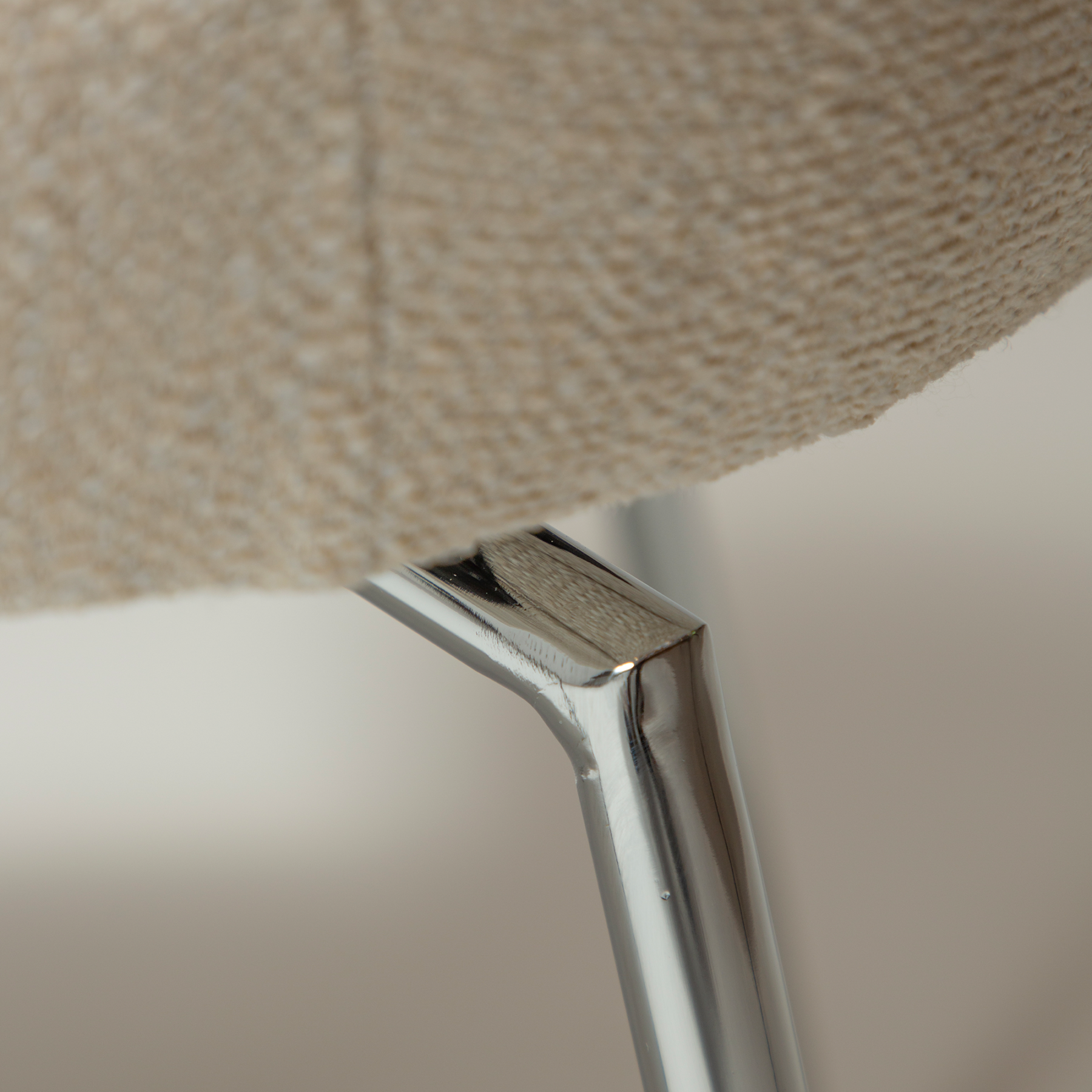 glam-chair-swivel-simply-beige-boucle-w-chrome-swivel-legs_100208323-06-detail1 Close up of the detail of the glam chair swivel in simply beige boucle fabric with chrome legs.