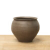 Medium brown ceramic vase with a rounded shape, flared rim, and earthy finish on a wooden surface.
