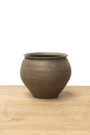 Medium brown ceramic vase with a rounded shape, flared rim, and earthy finish on a wooden surface.