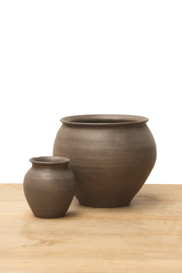 Medium brown ceramic vase with a rounded shape, flared rim, and earthy finish on a wooden surface.