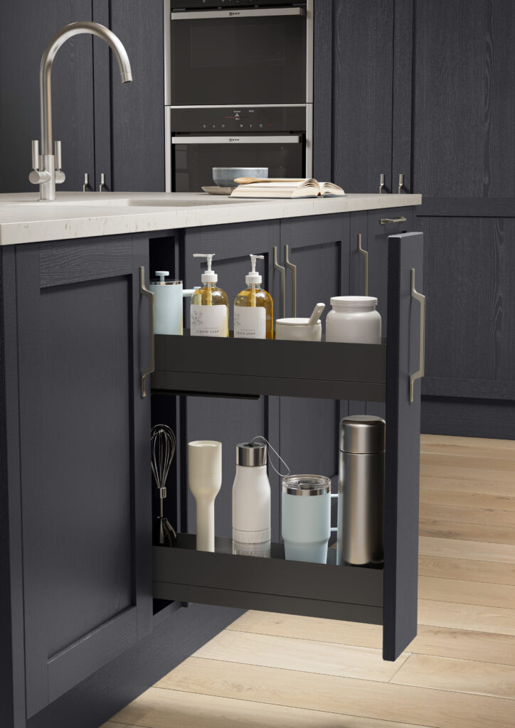 Slim pull-out storage cabinet beside sink in a navy shaker kitchen.