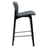 paragon-counter-stool-pebble-grey-fabric-black-stained-ash-legs-side Paragon counter stool upholstered in Pebble Grey fabric with black-stained ash wood legs, featuring a curved seat and backrest for modern kitchen islands and breakfast bars.