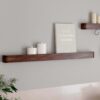Protopia wall shelf in walnut veneer with a slim profile and curved ends, ideal for displaying artwork, books, photographs, and decorative accessories.
