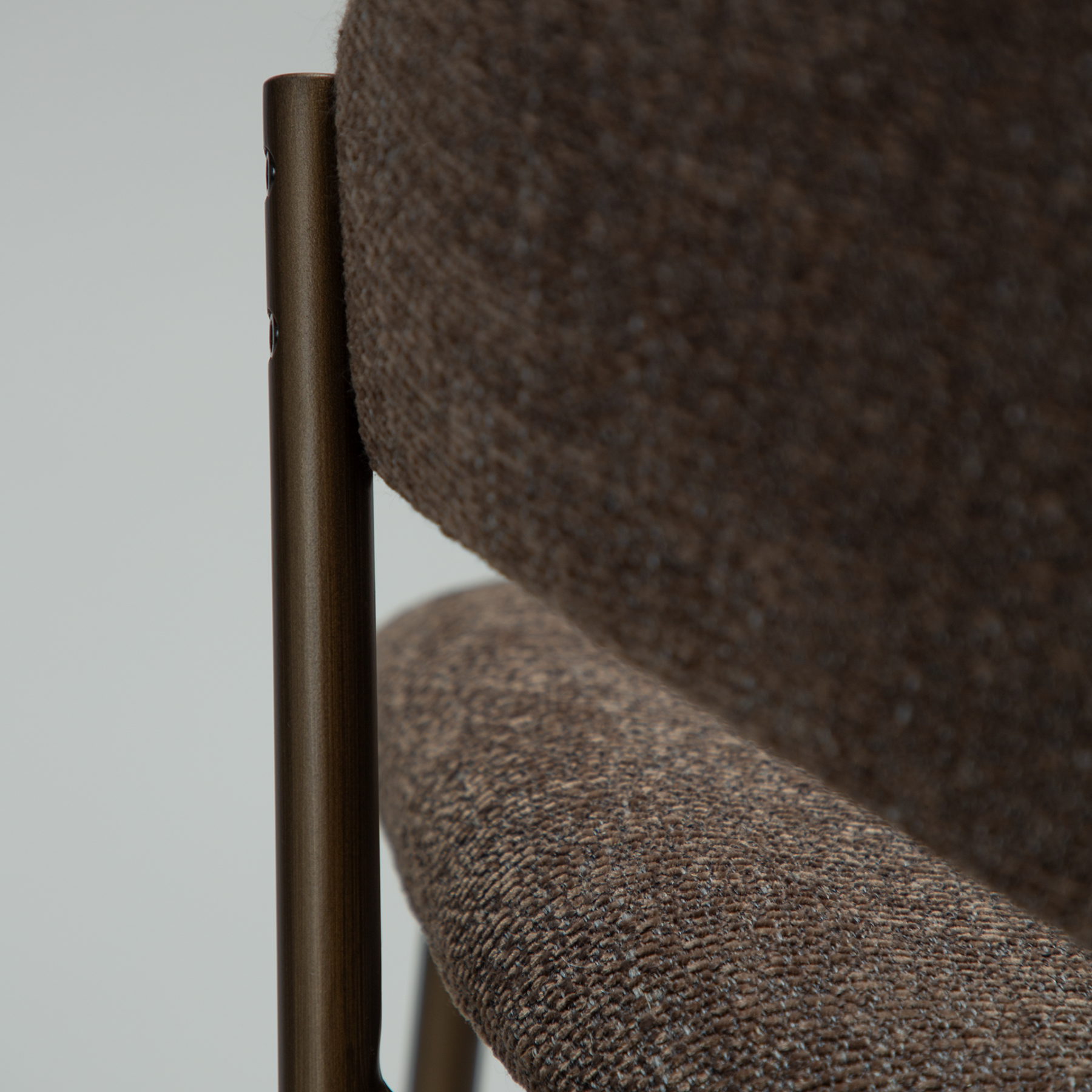 zone-dining-chair-major-brown-boucle-antique-brass-legs-close ZONE dining chair upholstered in Major Brown bouclé fabric with antique brass legs, featuring a curved Scandinavian-inspired backrest for modern dining spaces.