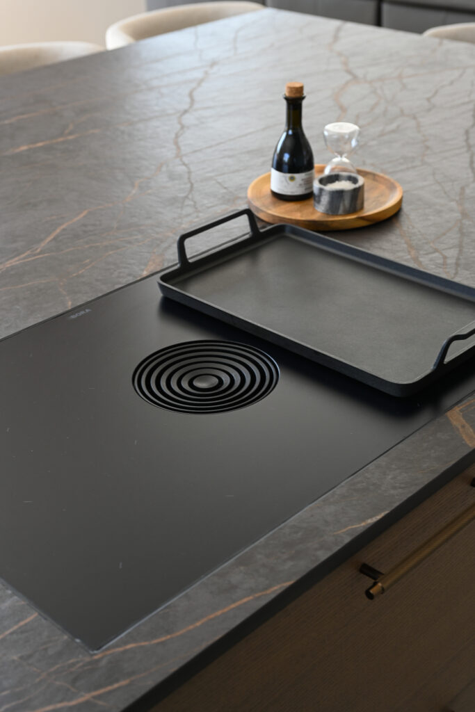 Close-up of a BORA downdraft hob with grill pan set into a dark stone kitchen island.