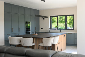 Bright white Shaker utility room with fitted laundry appliances, sink, drying rail and bespoke floor-to-ceiling storage.