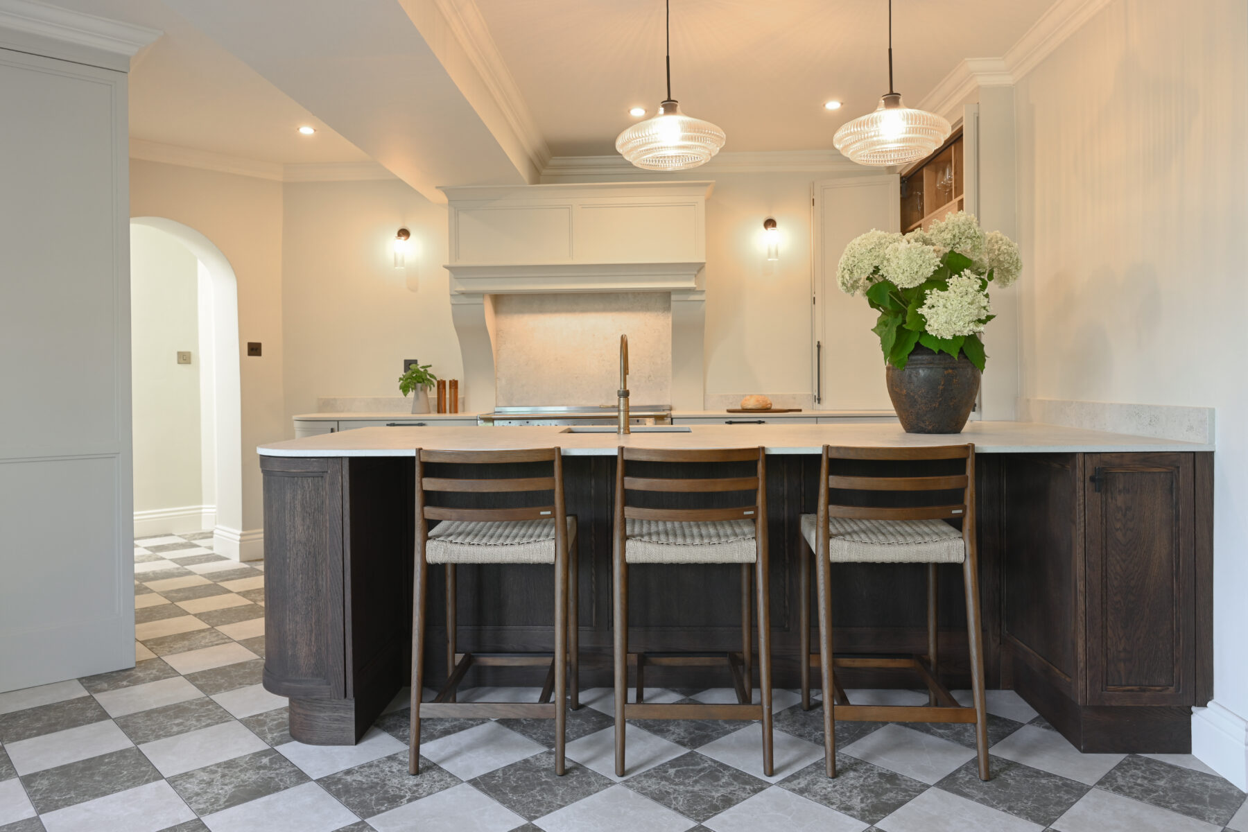 Bespoke two-tone kitchen with a dark timber island, light painted cabinetry, stone worktops and pendant lighting.