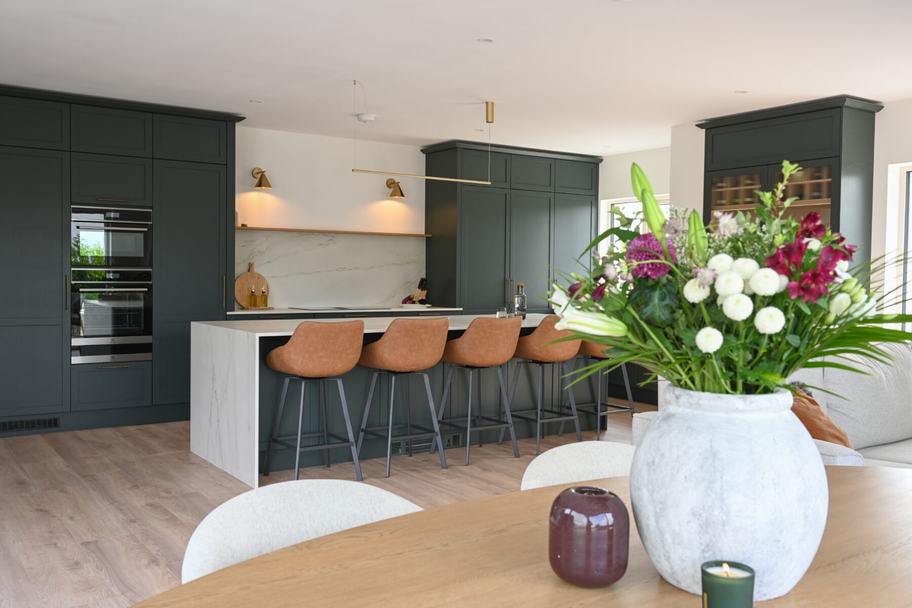 Deep Forest green Shaker kitchen with a large stone island, integrated appliances, pantry storage and open-plan dining area.
