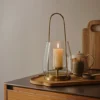 nilo-lantern-brass-metal-glass-lifestyle Nilo Lantern in brass-finish metal and clear glass with a tall contemporary design
