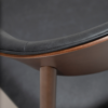 ravish-armchair-raven-black-walnut-veneer-legs-close-up Ravish Armchair in Raven Black upholstery with curved walnut veneer back, integrated armrests and walnut legs.