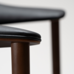ravish-armchair-raven-black-walnut-veneer-legs-zoom Ravish Armchair in Raven Black upholstery with curved walnut veneer back, integrated armrests and walnut legs.