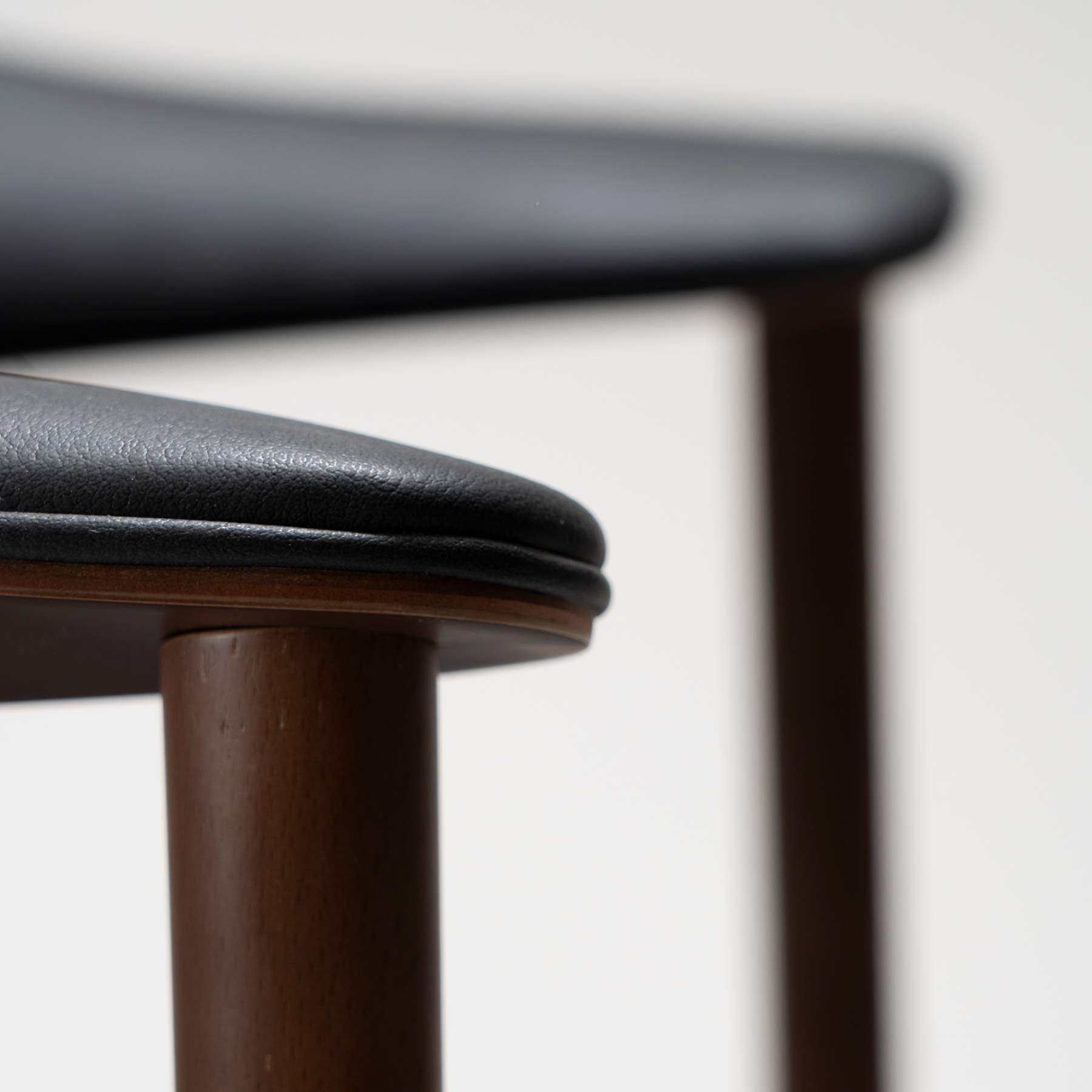 ravish-armchair-raven-black-walnut-veneer-legs-zoom Ravish Armchair in Raven Black upholstery with curved walnut veneer back, integrated armrests and walnut legs.