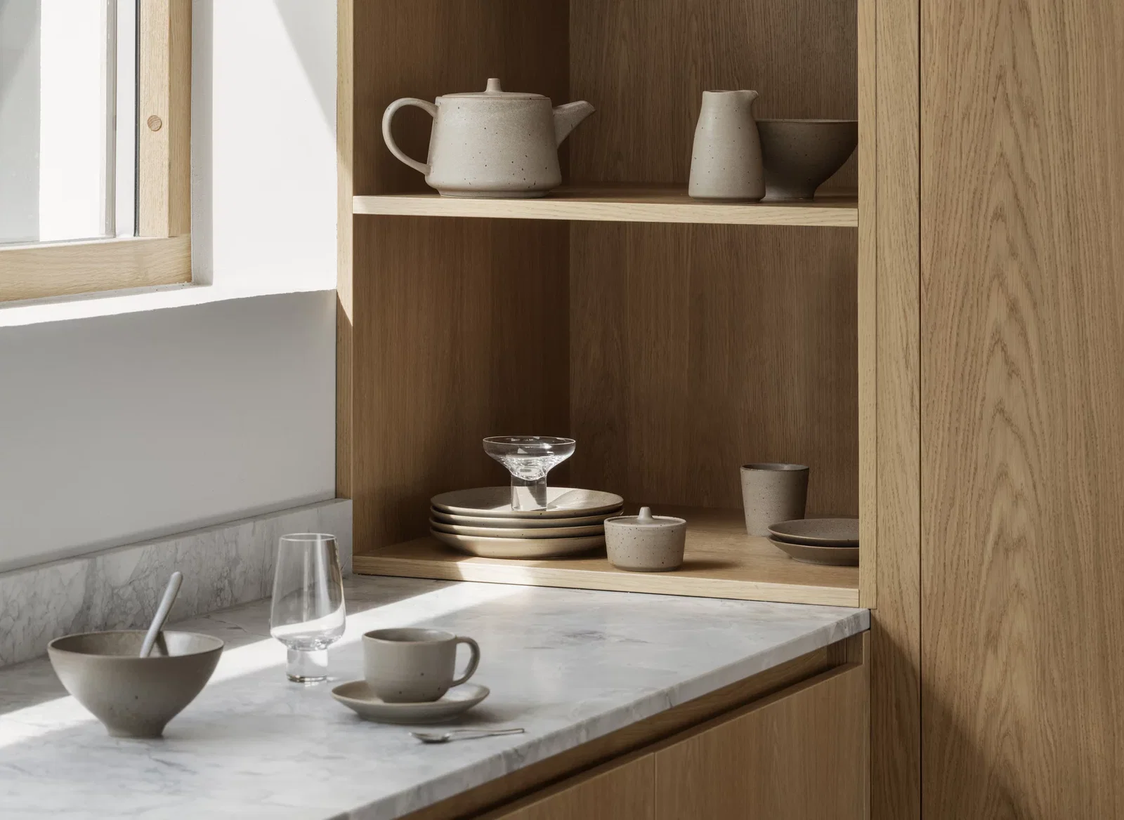 Koyoi Champagne Coupe in clear glass styled on oak kitchen shelving with neutral tableware