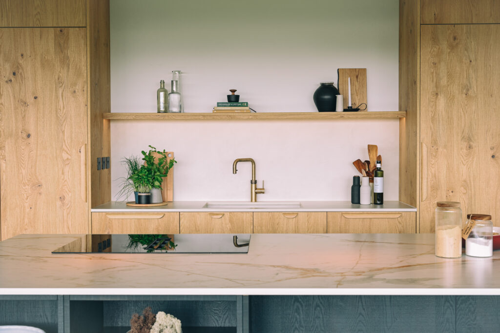 Bespoke oak veneer kitchen with Dekton Albarium wall run, Dekton Reverie island, Quooker tap and contrasting black island cabinetry.